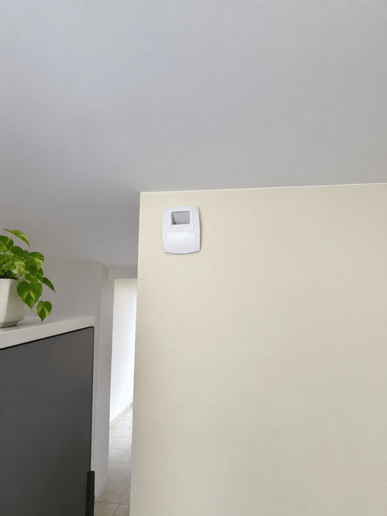 Bouche d'extraction blanche posée en haut de mur dans une cuisine, raccordée au réseau de ventilation du logement