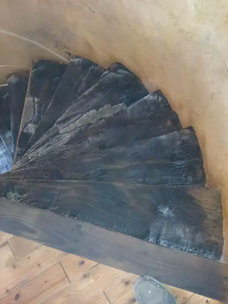 Vue plongeante sur un escalier ancien aux marches sombres lors de travaux de sablage du bois à Lannion.