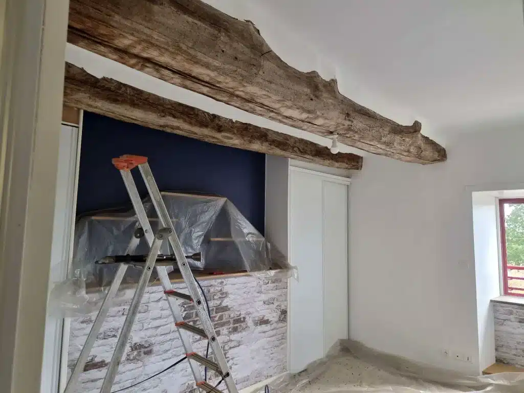 Solives anciennes en bois et murs en pierre dans des combles, avant travaux de traitement du bois à Lannion.